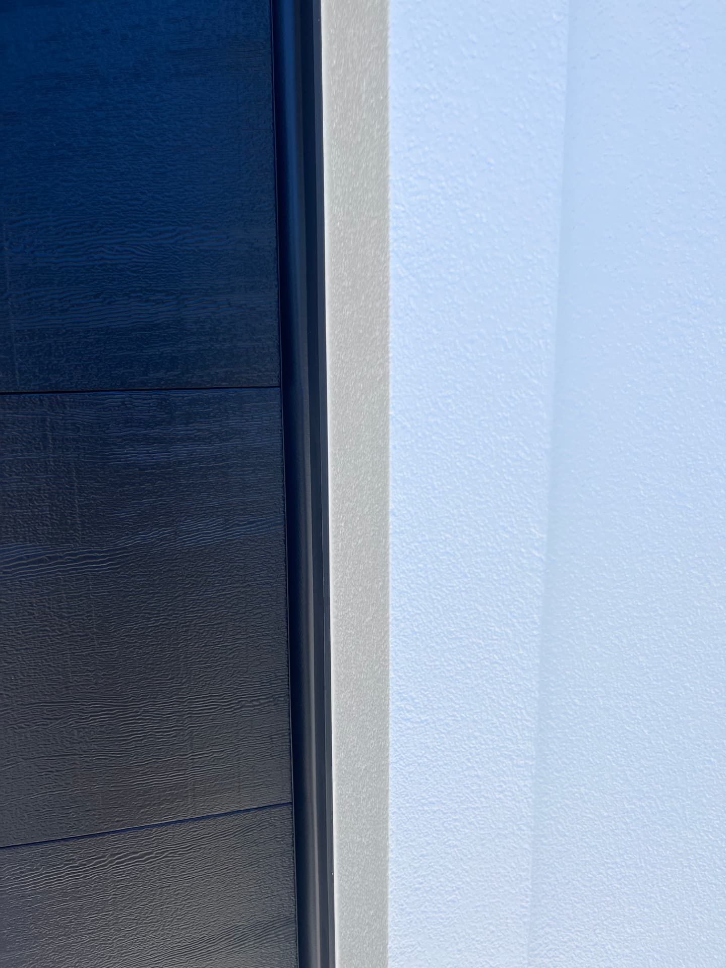 Close-up of a clean paint line between navy siding and white trim