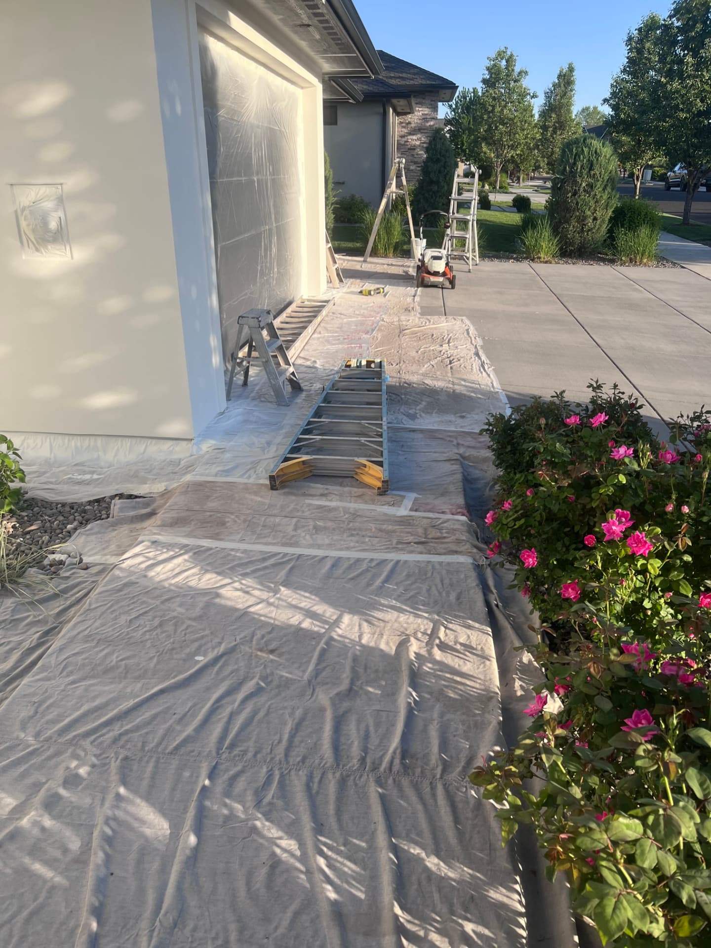 Driveway and garage masked off with drop cloths during surface preparation