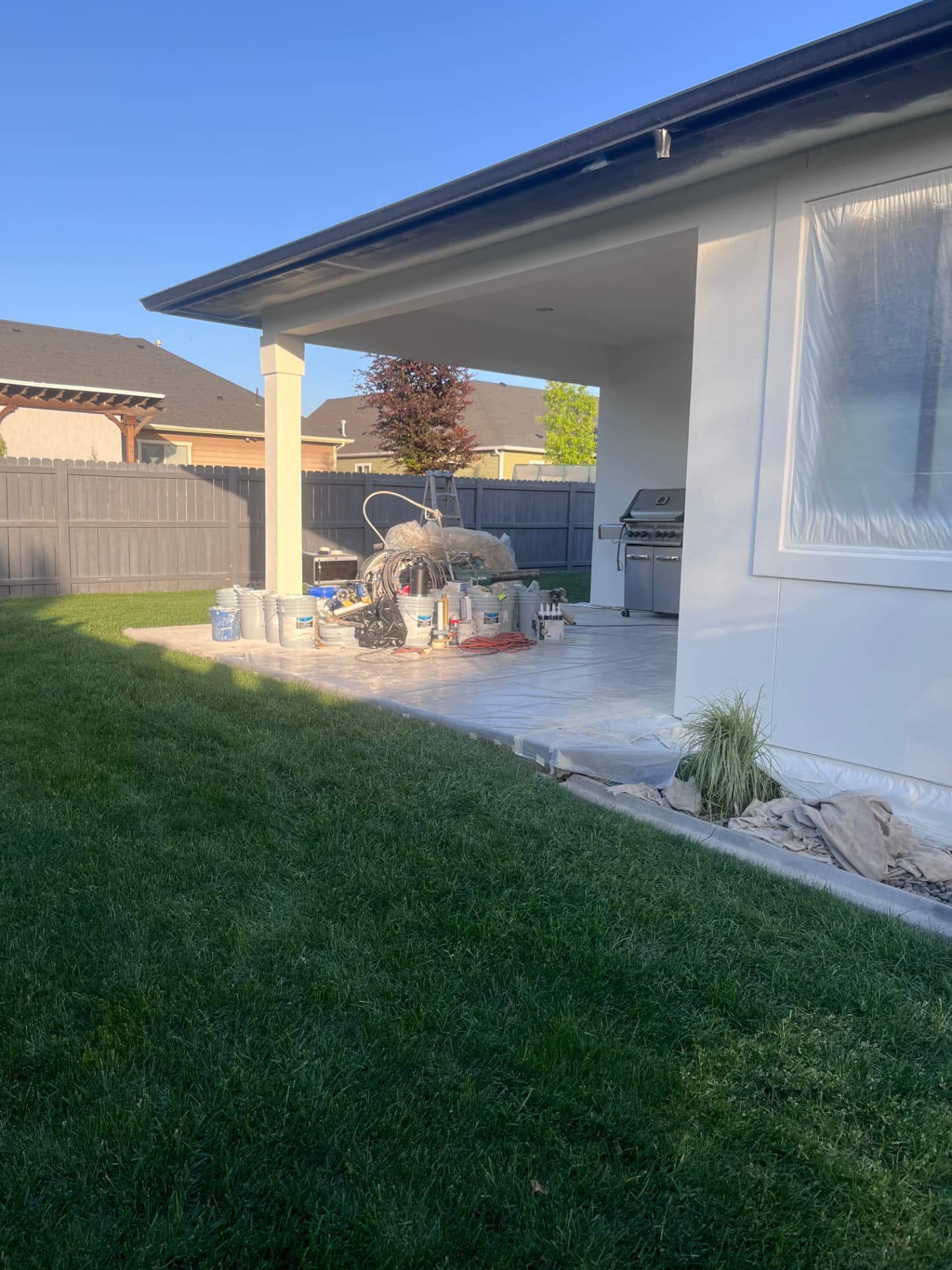 Covered patio, grill, and landscaping fully masked and protected before painting